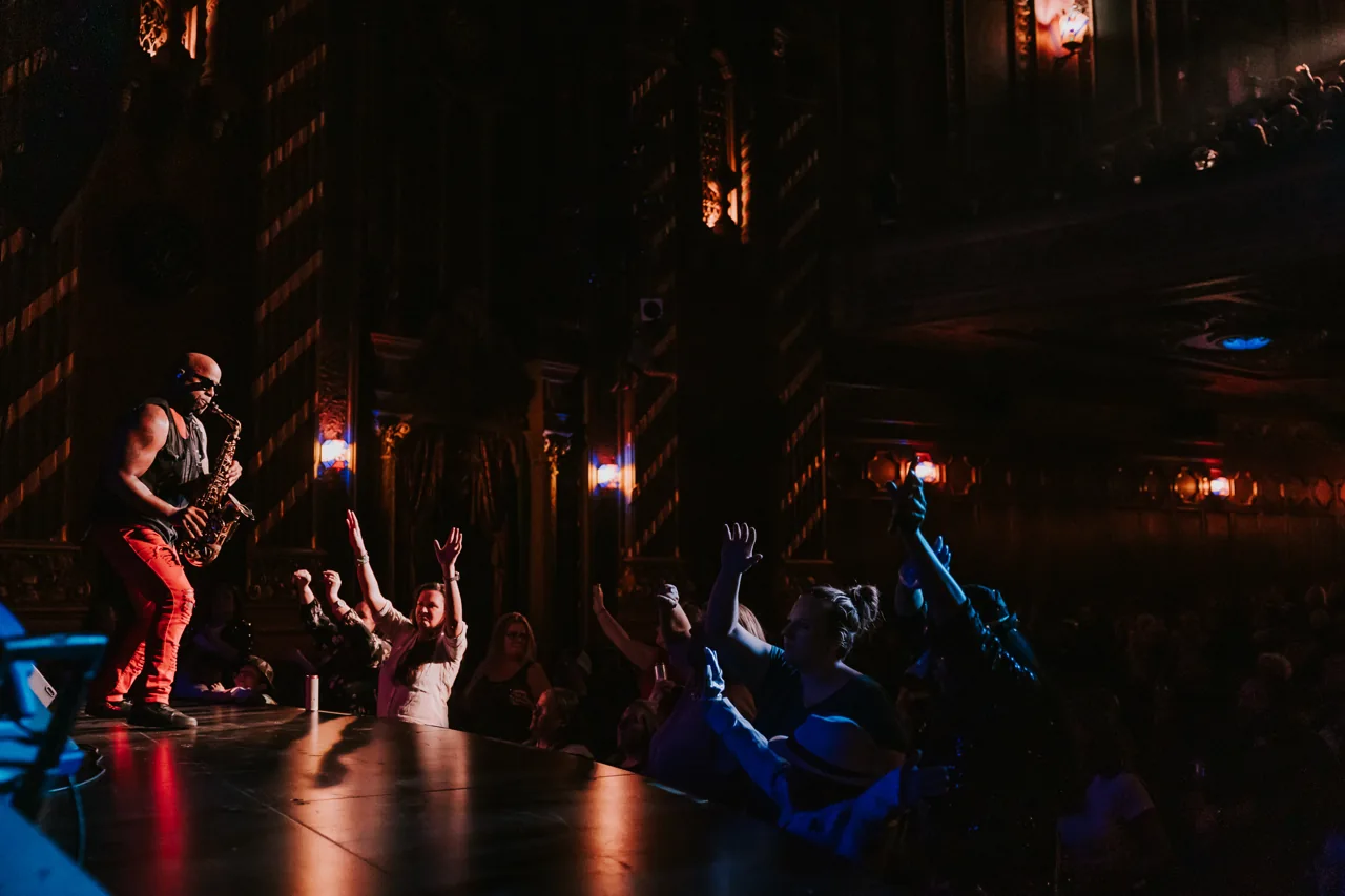 A Who’s Bad performer in a red jacket reaches towards a packed concert audience
