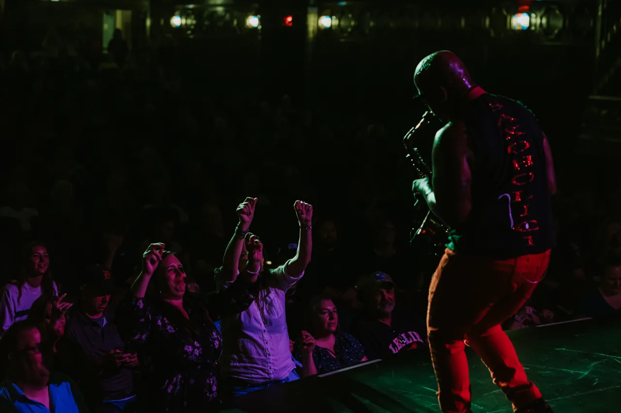 A Who’s Bad performer in red trousers faces fans reaching up from the audience